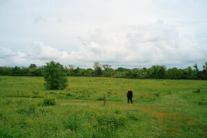 Jason standing in a field under a cloudy sky